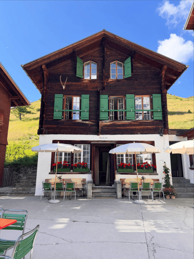 Traditional Swiss chalet with green shutters and outdoor café tables