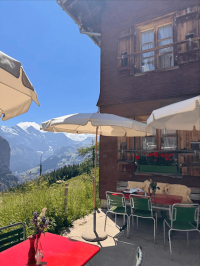 Alpine café terrace with white umbrellas overlooking snow-capped mountains