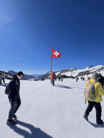 Visitors on the snow at Jungfraujoch beside the Swiss flag