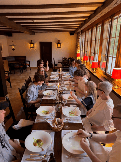 Candlelit group dinner at a long table in a wood-beamed dining room