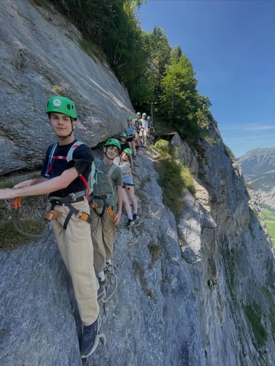 A line of climbers with helmets and harnesses on a via ferrata cliff path