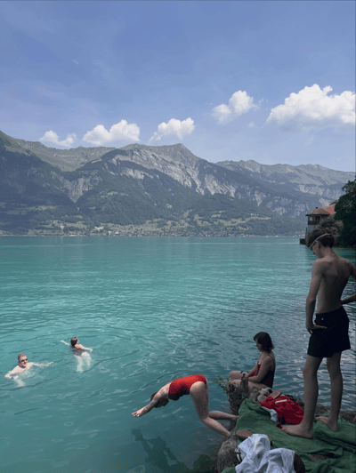 Swimmers in the turquoise water of Lake Brienz with mountains behind